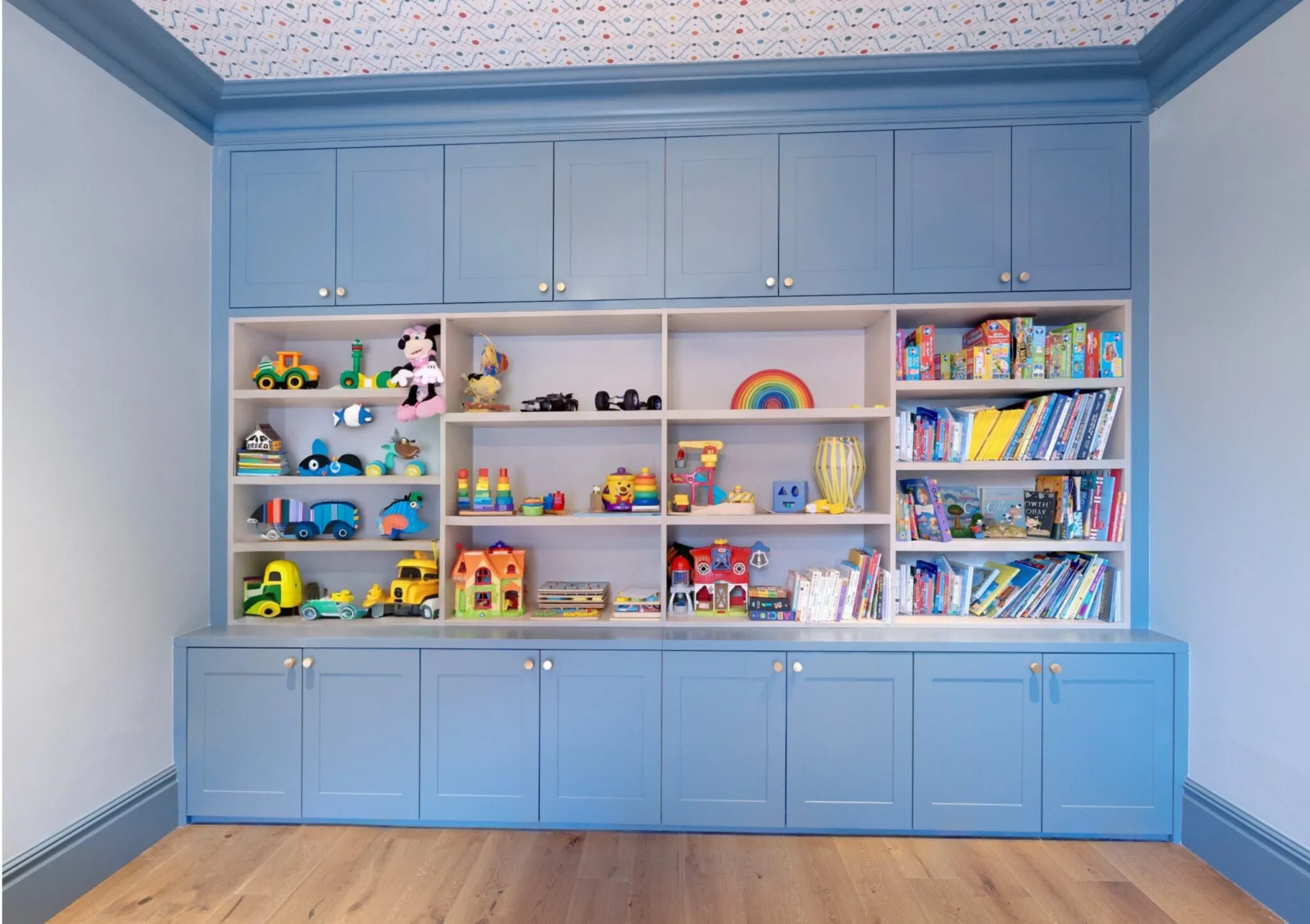 Blue Shaker-style playroom storage with open shelves full of toys and books