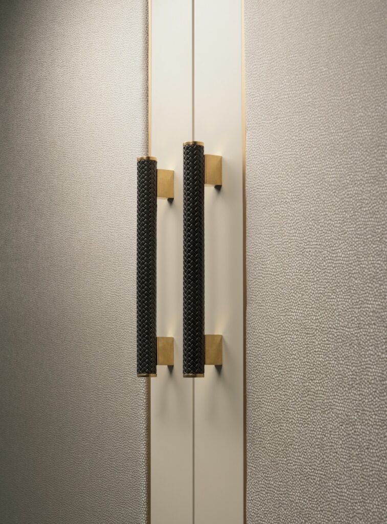 Close up of textured handles on Belgravia wardrobe. Grey stippled fabric covering doors of wardrobe.